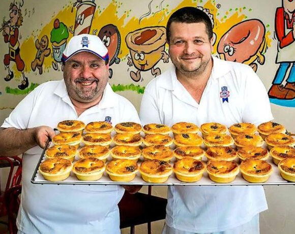 Two happy bakers with a tray of delicious meat pies