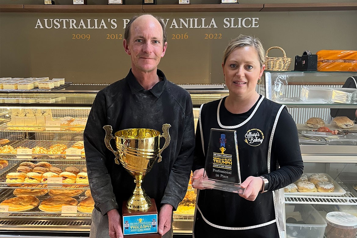 Brad and Tara Sharp stand in their bakery holding the trophies for winning (vanilla slice)