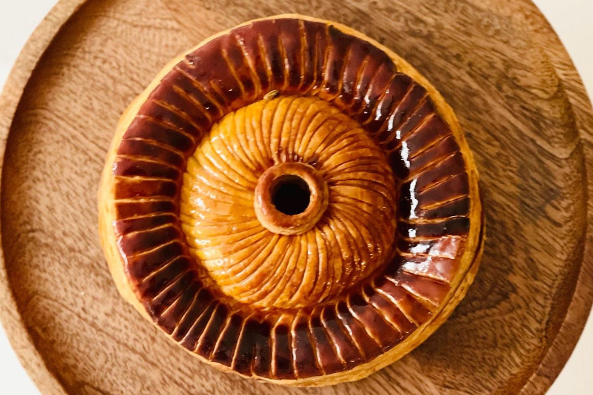 A pithivier sits on a wooden board, image shot from above (LoDe Pies)
