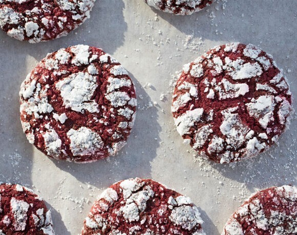 Red velvet crinkle cookies on a piece of baking paper, duster with icing sugar