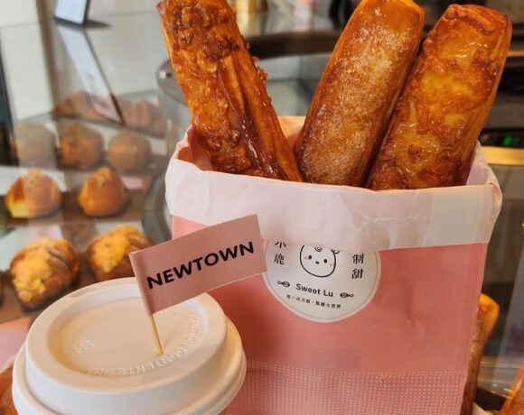 A paper back full of breadsticks sits next to a takeaway coffee cup with a cocktail flag with the word 'Newtown' on it sticking out of the top (Sweet Lu)