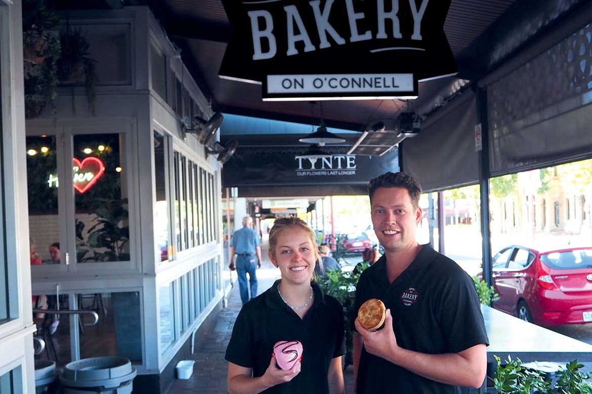 Amelia Greven and James Kent in front of the Bakery on O'Connell sign