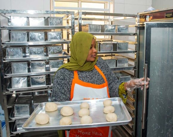 A woman places a tray full of buns in an industrial oven (Olam Agri)