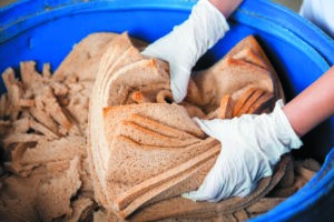 Baker's Hands Discarding Bread Waste In Garbage Bin