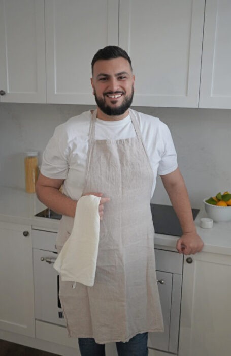 Anthony Silvio from Vannella Cheese stands in a kitchen wearing a beige apron and holding a white tea towel