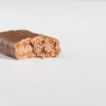 A Tim Tam biscuit rests on a white background. A bite has been taken out of the side facing the camera.