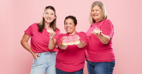 Bakers Delight Pink Bun campaign faces Jill, Kansas and Sam are pictured all in denim jeans and pink shirts. They stand in front of a pink background and each hold a bun topped with pink icing and sprinkles.